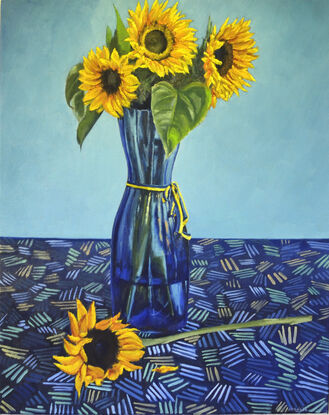 Golden yellow sunflowers in blue glass vase kept on a patterned table cloth   