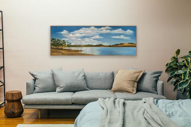 Lake bordered by hills and trees and reflecting blue sky and clouds.