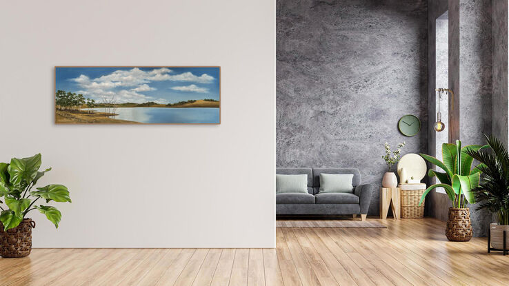 Lake bordered by hills and trees and reflecting blue sky and clouds.