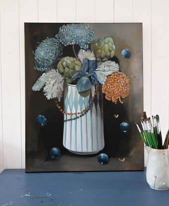 A tall geometrically patterned vase holds a couple of green artichoke stems and other flowers. The background is a neutral tone of grey brown. The painting captures the passing of time in a still life. 
This  painting was exhibited in a prominent Brisbane gallery in April of 2024. 