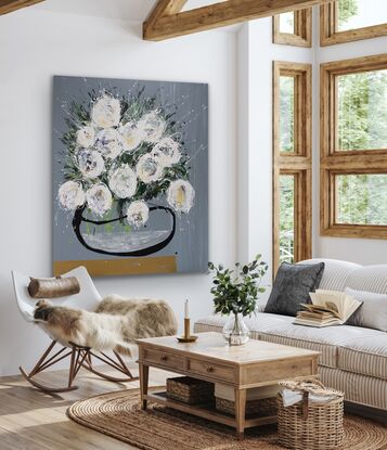 Large white abstract flowers in an organic black vase, sitting on a gold shelf.  Medium grey background.  A largescale statement piece with natural tones.