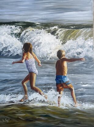 A young boy and girl run in opposite directions arms out flung as they face a wild breaking wave. The ocean is a churning mass of water and the last light of the day paints the children gold.