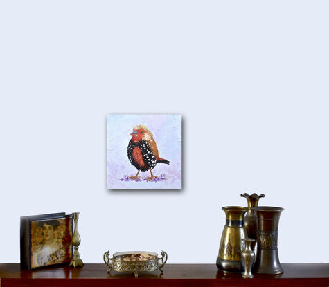 Heavily textured oil painting of a young Painted Firetail Finch bird on a pale lavender background. This little bird is native to Australia and named the Painted Firetail finch due to the red and white spotted and mottled underparts of both males and females. 