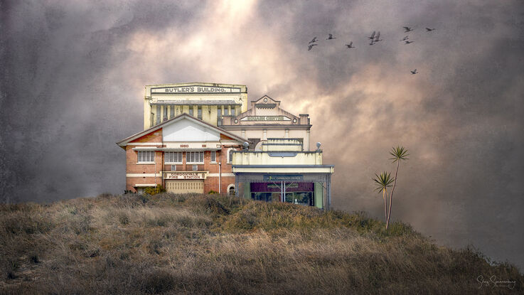 A complex of similar buildings of retro and art deco architecture fused together as one sharing a grassy hill setting and textured moody sky background. A flock of  birds fly by plus a lone pandanus palm decorates the hill.