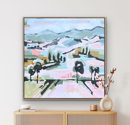 Large framed canvas with a textured landscape scene in pastel tones of orange, pinks, blues and greens. Abstract hills, trees and foliage shapes chunky paint with visible big brushstrokes.