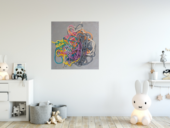 A birds eye view of a colourful pile of woollen threads on a grey background.