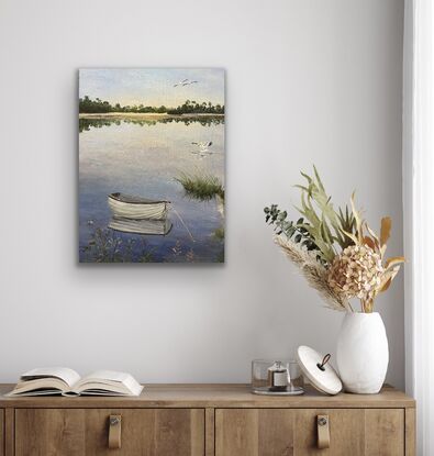 Pelicans fly overhead  and a boat is reflected in still water with reeds on the shore.