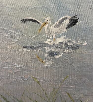 Pelicans fly overhead  and a boat is reflected in still water with reeds on the shore.