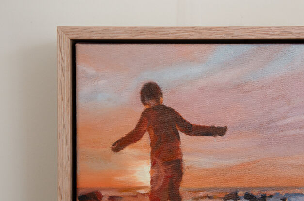 Boy stepping across stones at the beach at sunset.