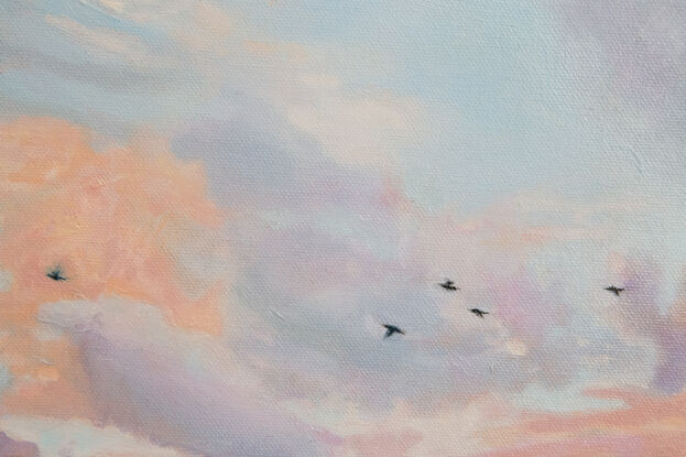 Three birds flying with a sunrise in the background.