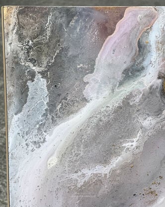 This artwork features an abstract composition with a mix of muted tones, predominantly soft grays, whites, and subtle hints of pink and mauve. There are patches of gold leaf that add a touch of metallic texture and depth to the piece. The overall effect is reminiscent of a dreamy, ethereal landscape, possibly evoking the feel of swirling clouds or a misty, mountainous terrain. 

