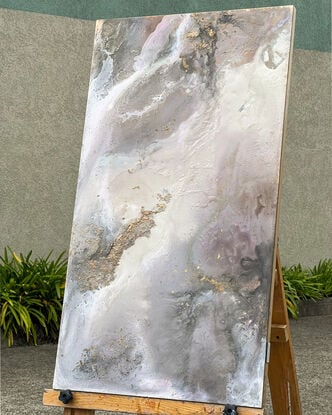 This artwork features an abstract composition with a mix of muted tones, predominantly soft grays, whites, and subtle hints of pink and mauve. There are patches of gold leaf that add a touch of metallic texture and depth to the piece. The overall effect is reminiscent of a dreamy, ethereal landscape, possibly evoking the feel of swirling clouds or a misty, mountainous terrain. 

