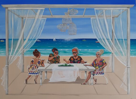 Four women sitting at a table by the beach