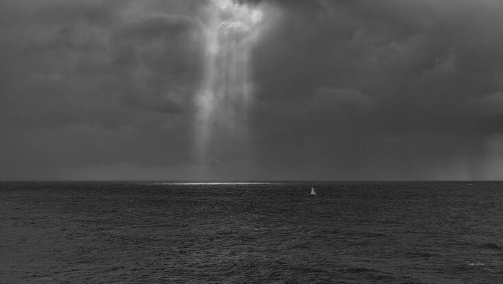 Original photograph dramatic image sail boat on vast ocean with sun bursting through clouds