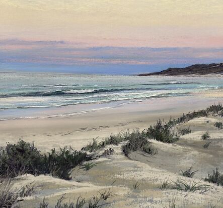 Headland with a bright sunny sky aqua water  hues of pink and yellow in the sky and soft sand dunes in the foreground 