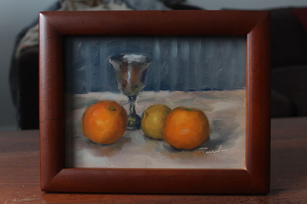 An original oil painting of a silver goblet and oranges.