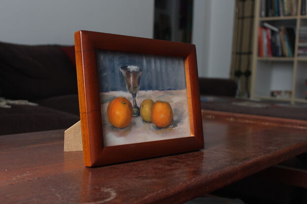 An original oil painting of a silver goblet and oranges.