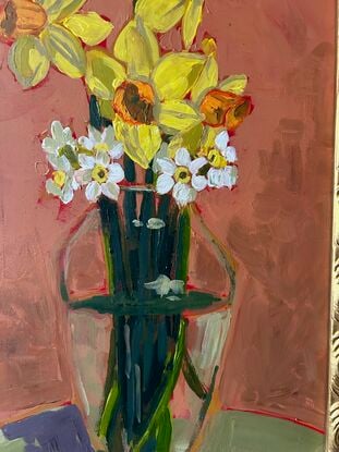 A clear rounded tall glass vase with butter yellow daffodil stesm mixed in the cream white jonquis and green grey strappy foliage. The background is ocre and the frame is gilt art nouveau in style