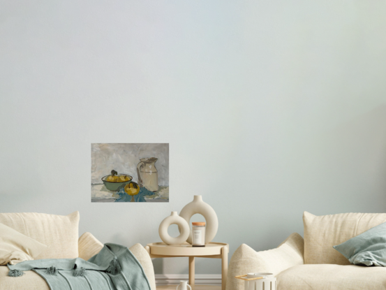 A still life scene with light green enamel bowl with light yellow nashi pears in it. To the right is an old ceramic cream coloured milk jug and they both sit on a light blue tea towel crumpled underneath. The background is white