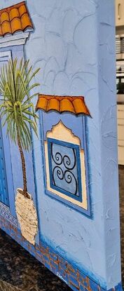 Quintessential image of Chefchaouen Morocco with large arched timber door, heavy plaster walls, aged and worn pots and cobblestone - blue of course.  The opened door provides a peek into the courtyard of the Riad acccommodation with its gorgeous aqua pool reflecting the arched architecture.