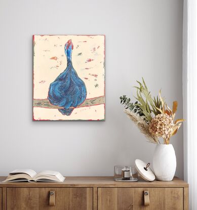 Guinea fowl with head raised and mouth open perched on a large stick with a cream background.