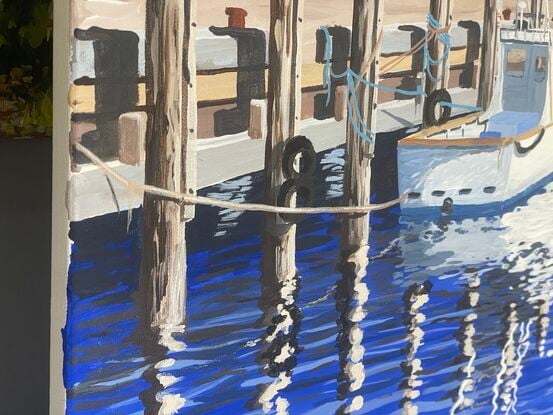 Sunny winter day, depicting fishing boats and yachts, and their reflections, tied up to a jetty.