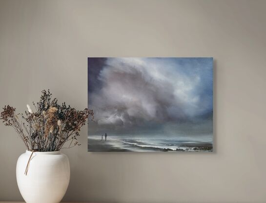 Two people walking on a beach with storm clouds overhead.