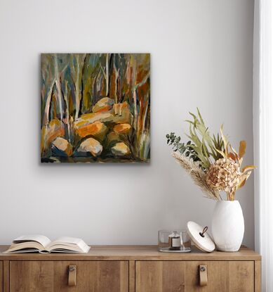 This painting is made from a river scene, the boulders and rocks rise from the rivers edge up to forest of trees.  The trees are depicted by paintbrush strokes in a variety of colours, the main trees are left as off white.  The scene is  a warm  and peaceful setting.