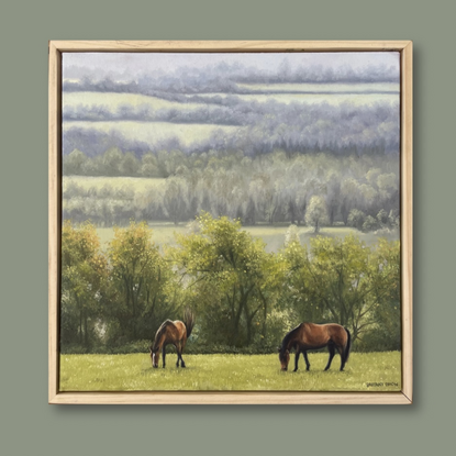 A framed oil painting of two horses grazy in a field with rain-swept, misty fields in the distance.