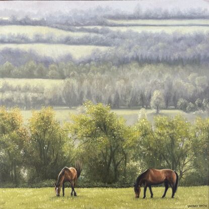 A framed oil painting of two horses grazy in a field with rain-swept, misty fields in the distance.