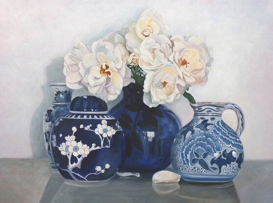 White iceberg roses in a blue and white ceramic vase, with other vases. 