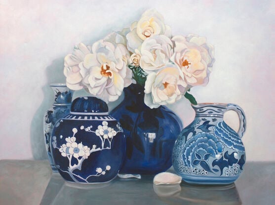 White iceberg roses in a blue and white ceramic vase, with other vases. 