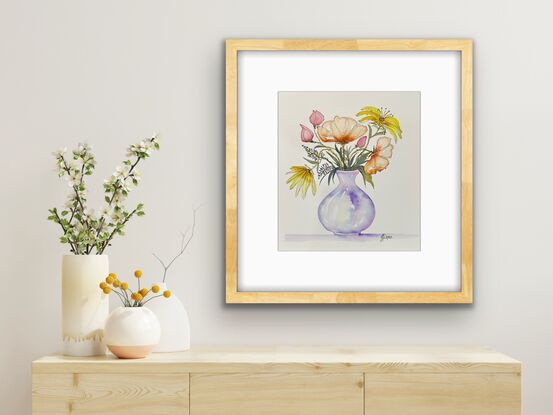 A bouquet of pretty flowers in yellow pink and orange in a round mauve vase