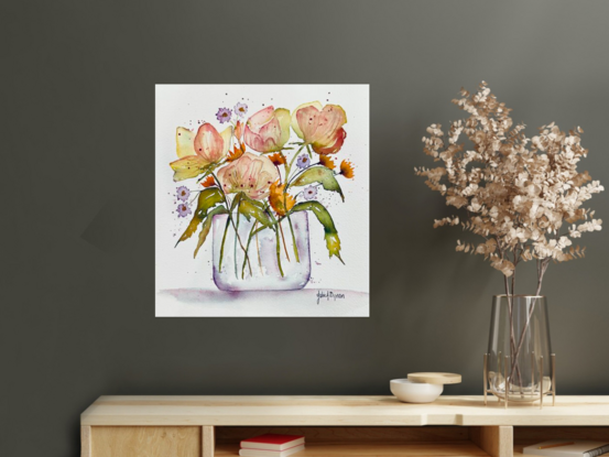 A bouquet of soft pastel flowers in orange yellow and mauve in a glass vase