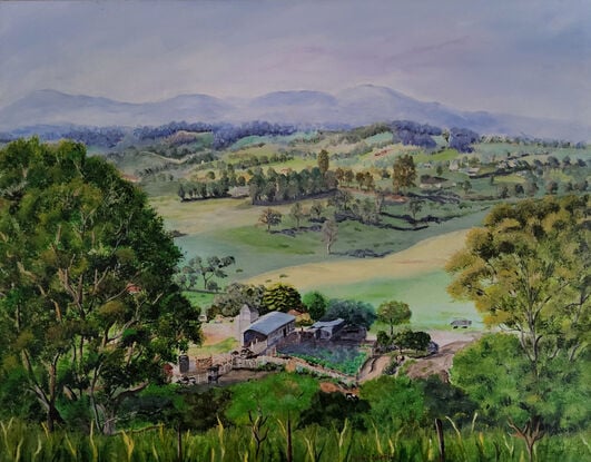 a panoramic view to the misty mountain ranges in the distance and the rolling hills of Bega Valley, with homes scattered around, surrounded by grasses, shrubs and trees with a working farm in the foreground and tall grasses and a hint of a fence in front, all framed by two large gum trees on either side of the artwork