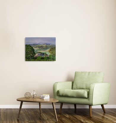 a panoramic view to the misty mountain ranges in the distance and the rolling hills of Bega Valley, with homes scattered around, surrounded by grasses, shrubs and trees with a working farm in the foreground and tall grasses and a hint of a fence in front, all framed by two large gum trees on either side of the artwork