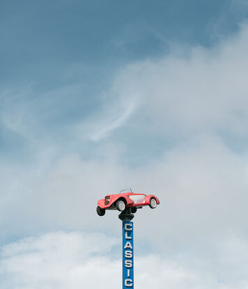 Minimalist landscape photo of a classic car on a pole in New Zealand