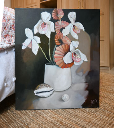 A white vase with orchids and a fan mushroom stem. A cowrie shell is in front to  the left and an oversized pearl is positioned in the foreground.