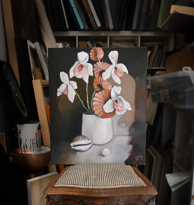 A white vase with orchids and a fan mushroom stem. A cowrie shell is in front to  the left and an oversized pearl is positioned in the foreground.