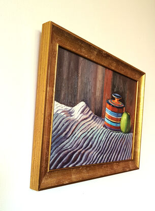 Green apple contrasted against an orange jar on  a striped fabric with light falling on them from the left direction 