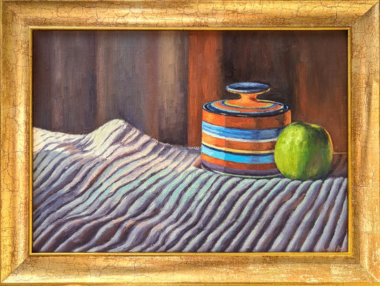 Green apple contrasted against an orange jar on  a striped fabric with light falling on them from the left direction 