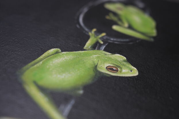 Two green tree frogs on a wine glass with a black background.