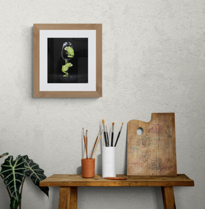 Two green tree frogs on a wine glass with a black background.