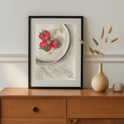 The artwork is a watercolor painting of a white plate with three strawberries and a few daisies. The strawberries are a vibrant red and the daisies are a soft white. The plate is cast in shadow, creating a sense of depth and realism. The overall effect is one of freshness and summer.