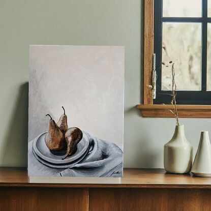 This artwork is a still life painting featuring three brown pears resting on a white plate and a grey cloth. The pears are depicted realistically with subtle variations in colour and texture. The background is a muted beige, providing a neutral backdrop for the composition. The overall tone of the painting is calm and understated, with a focus on capturing the simple beauty of everyday objects.