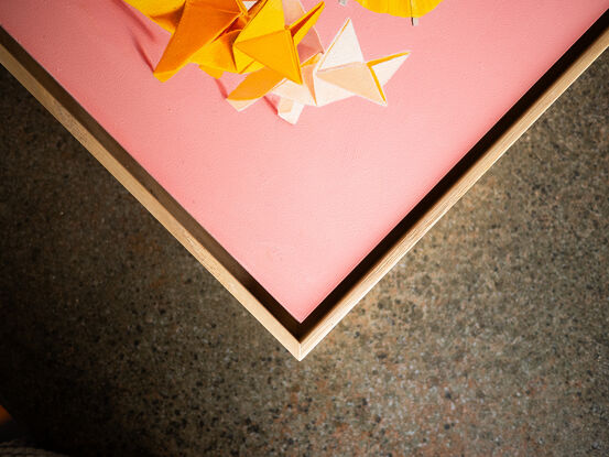 two origami foxes together under a cocktail parasol. the mood is fun and playful