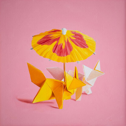 two origami foxes together under a cocktail parasol. the mood is fun and playful