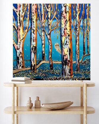 Several colourful gum tree trunks, an Emu looking out from behind  the trees with some leaf litter and twigs a lovely aqua blending upwards to bright blue sky 