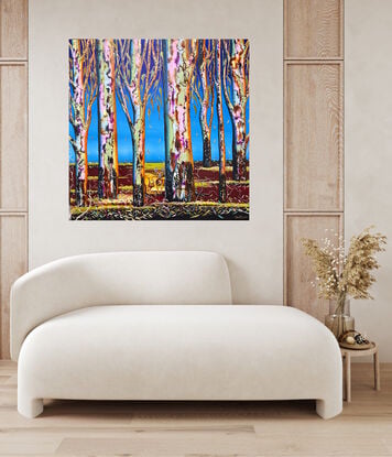 Several colourful gum tree trunks, a Kangaroo hiding in plain sight, with some leaf litter and twigs a lovely deep maroon with pops of green fading light blue upward to a bright blue sky 