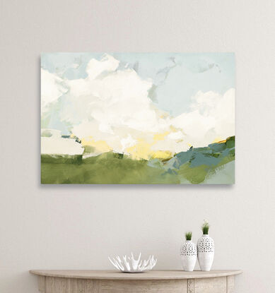 Loose abstract white clouds on a blue sky with touches of yellow  above a green and blue landscape.